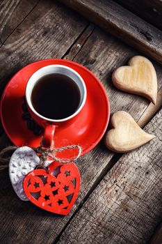 Red Cup with black coffee and two carved decorative wooden heart.Top view