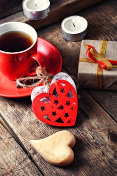 Red Cup with black coffee and decorative wooden heart.Selective focus