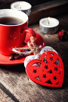 Red Cup with black coffee and decorative wooden heart.Selective focus