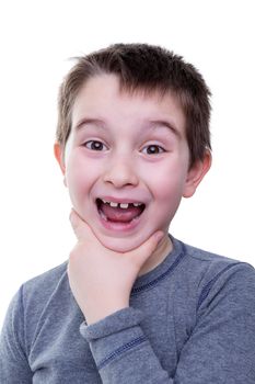 Cute little boy in gray shirt holding his chin with wide open mouth and big smile over white background