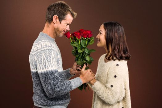Romantic couple holding red roses against shades of brown