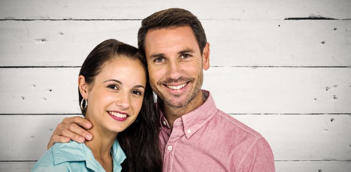 Smiling couple looking at camera against white wood