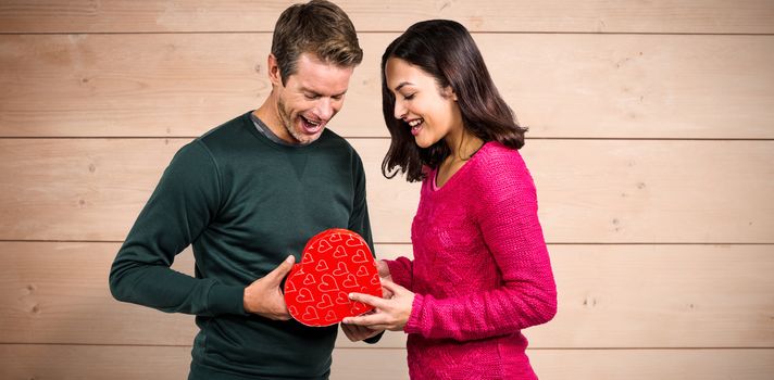 Happy young couple with heart shape gift against overhead of wooden planks