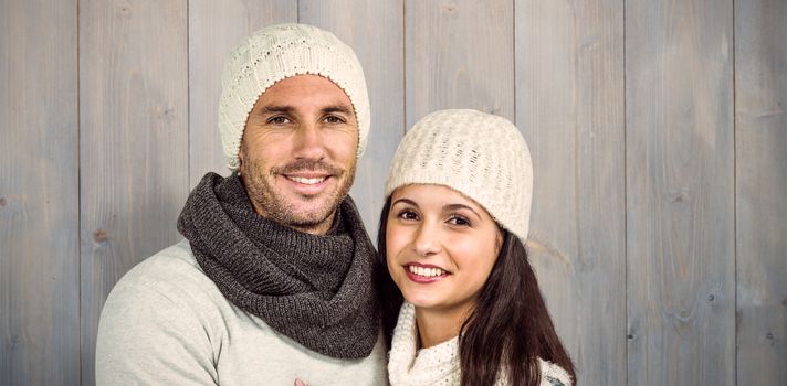 Smiling couple looking at camera against pale grey wooden planks
