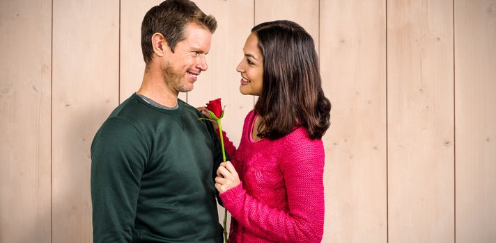 Smiling couple with red rose  against wooden planks
