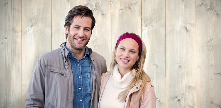 Smiling couple looking at camera against pale wooden planks