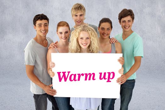 The word warm up and group of teenagers holding a blank card against grey wall