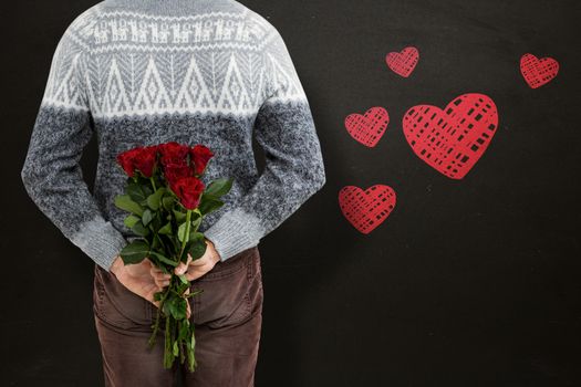 Mid section of man hiding red roses against blackboard