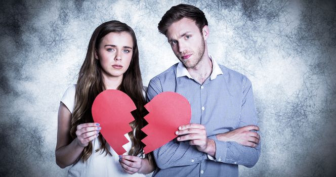 Couple holding broken heart against grey background