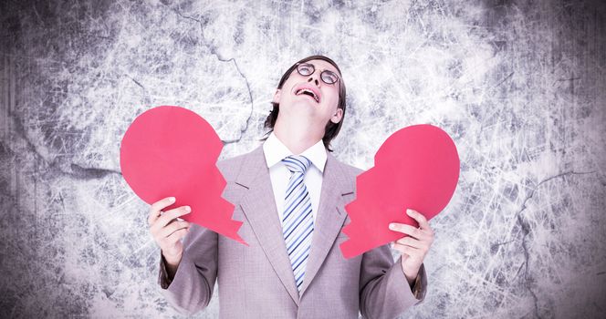 Geeky businessman crying and holding broken heart card against grey background