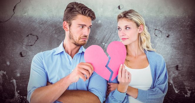 Couple holding two halves of broken heart against grey background