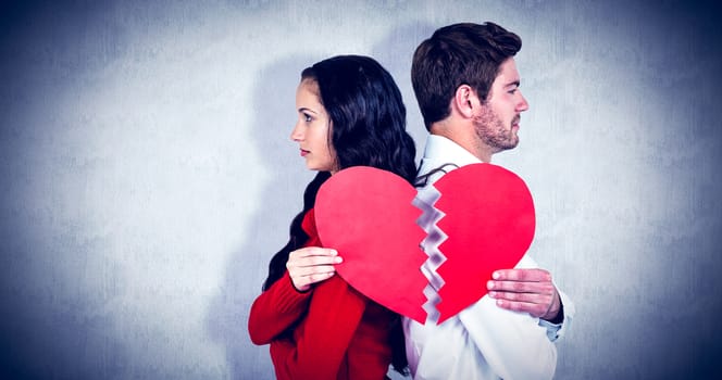 Couple back to back holding heart halves against white background