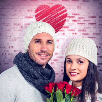 Smiling couple holding roses bouquet against grey room