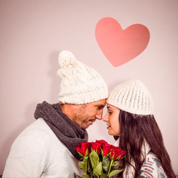 Smiling couple nose-to-nose holding roses bouquet against open door on white wall