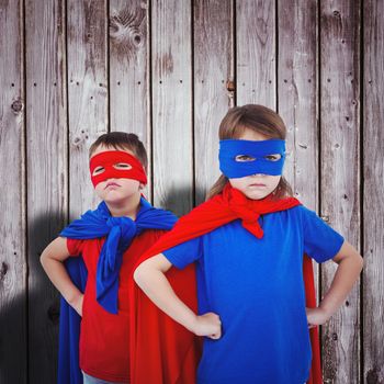 Masked kids pretending to be superheroes against digitally generated grey wooden planks