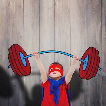 Little boy holding dumbbell against pale grey wooden planks