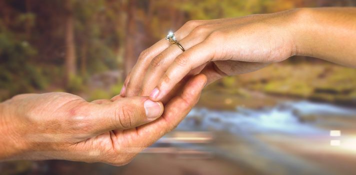 Cropped hand of couple holding hands against autumn scene