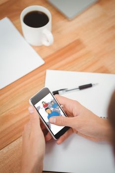 Businessman using smartphone at desk in office against view of communication network