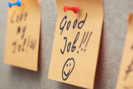 Adhesive note with Good Job text on a cork bulletin board