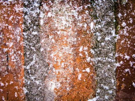 Detail of red brick and concrete wall lightly covered with snow flakes, winter time illustration, background, pattern
