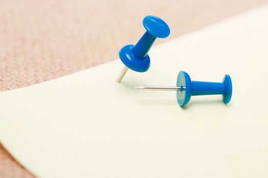 Adhesive note and blue pushpins. Close-up view