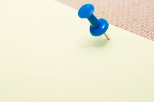 Adhesive note and blue pushpin. Close-up view