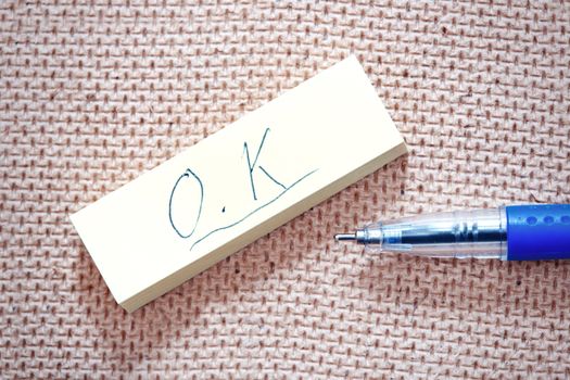 OK sign written on a label and blue pen