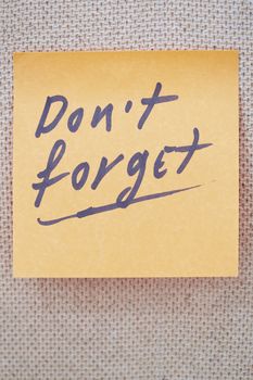 Adhesive note with Do not forget text on a bulletin board