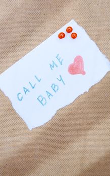 Call me written on a paper attached by pushpins to the wooden bulletin board