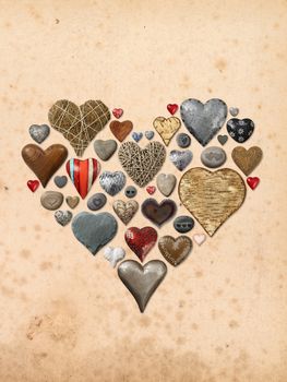 Photos of heart-shaped things made of stone, metal and wood, assembled into the shape of a heart over vintage paper background.
