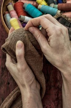 women's hands in the process stepania holey socks on the background of sewing thread