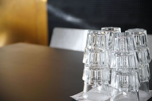 Clean drinking glasses stacked on a black table in a cafe.