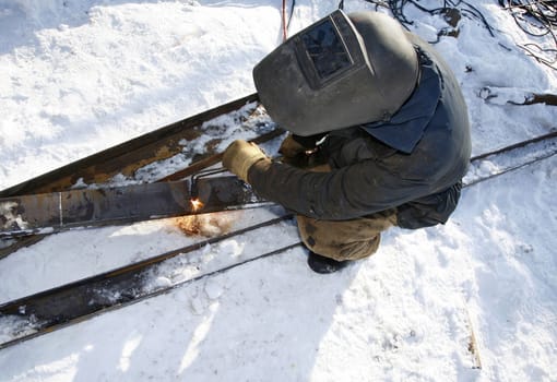 Industrial worker uses an acetylene torch in winter outdoor