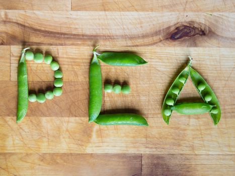 Word PEA created with peas on a wooden board