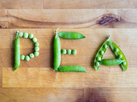 Word PEA created with peas on a wooden board