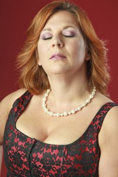red hair woman in in a red corset with her eye closes
