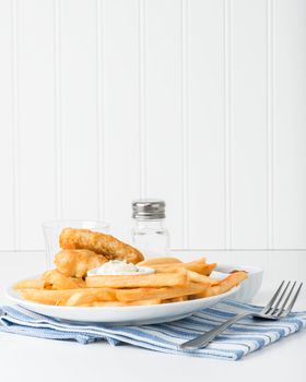 Deep fried potatoes are the main focus of the plate of fish and chips.