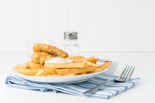 Golden deep fried potatoes with battered fish in the background.