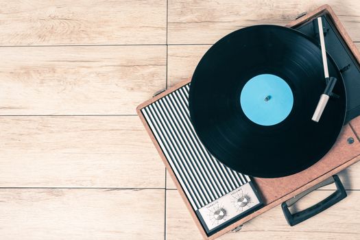 Gramophone with a vinyl record on wooden table, top view and copy space,photo desaturate and split toning for old style.