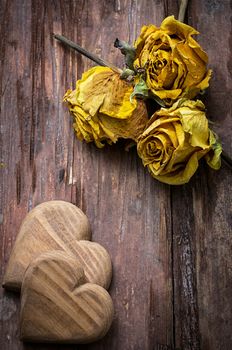 hand-carved symbolic wooden heart on a background of yellow roses