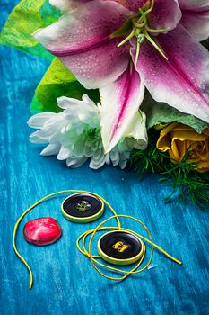 sewing accessories with a bouquet of fresh flowers on turquoise background