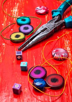 coil,beads and tools for needlework on red wooden background