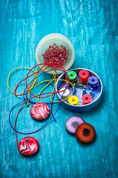 coil,beads and tools for needlework on turquoise wooden background