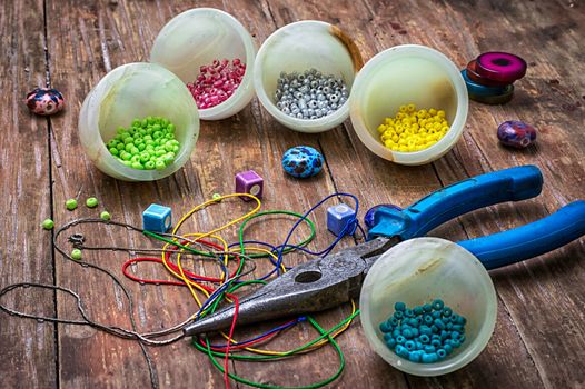 coil,beads and tools for needlework on turquoise wooden background