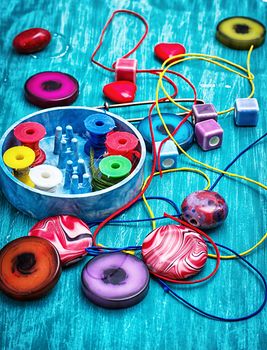 coil,beads and tools for needlework on turquoise wooden background