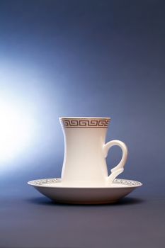 Stylish white coffee cup with saucer on dark background