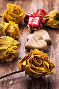 hand-carved symbolic wooden heart on a background of yellow roses