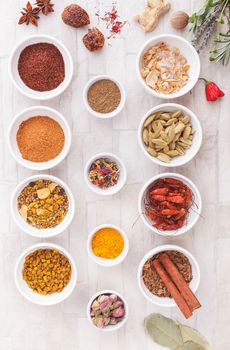 An arrangement of spices and herbs over rustic background. Top view, vintage toned image. Natural light