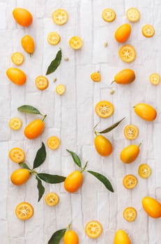 Kumquats whole and sliced, still life pattern background, overhead view