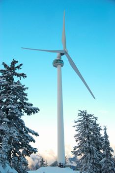 Wind turbine in the mountain covered with winter forest